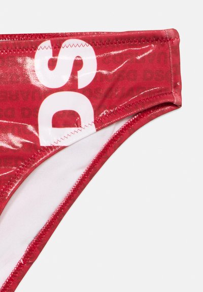 Bas de maillot de bain en tissu rouge brillant avec lettres blanches imprimées "DS" et couture zigzag visible le long des bords.
