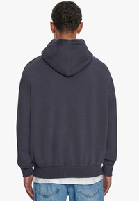 Bluza z kapturem w ciemnoszarym materiale frotte, o luźnym fasonie, z prążkowanymi mankietami i dołem. Gładka tekstura z klasycznym designem.