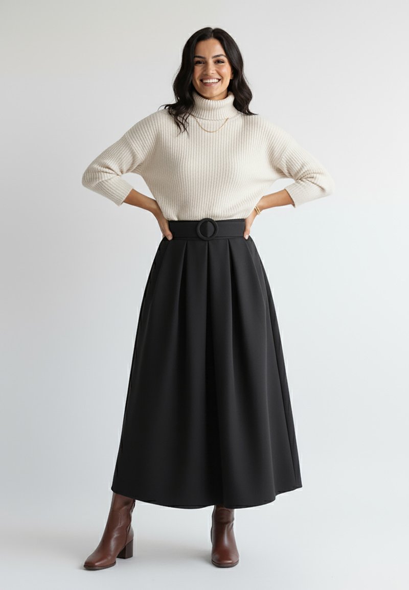Czarna plisowana spódnica maxi z szerokim paskiem zapinanym na okrągłą klamrę, zestawiona z kremowym prążkowanym golfem. Brązowe botki na obcasie.
