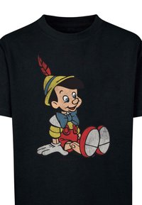 Camiseta negra con un gráfico colorido de Pinocho, con zapatos rojos, una camisa amarilla, un lazo azul y rasgos faciales detallados.