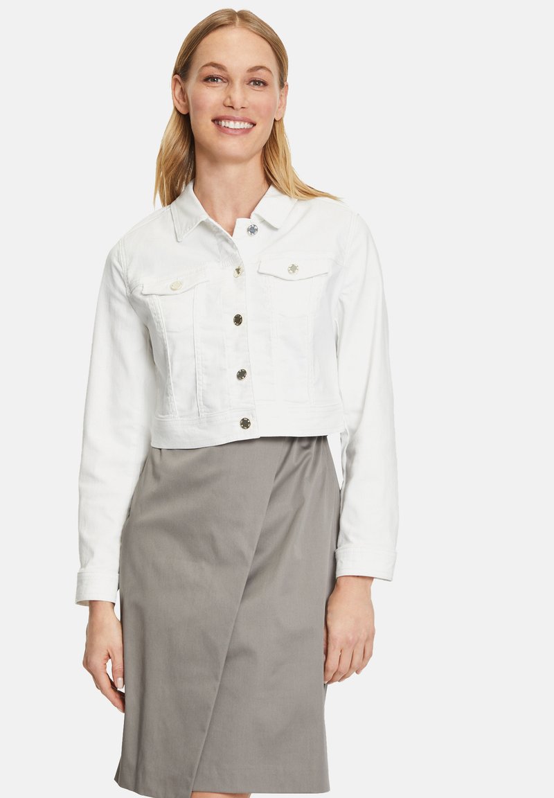 Witte gecropte denimjack met twee borstzakken en zilveren knopen, gecombineerd met een grijze wikkelrok. Soepele textuur, casual ontwerp.