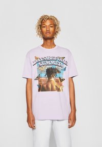 Tricou din bumbac lavandă, cu un print grafic ce prezintă o figură înconjurată de fluturi și textul "ZILE ÎNAINTE DE VARĂ." Gât rotund, mâneci scurte.