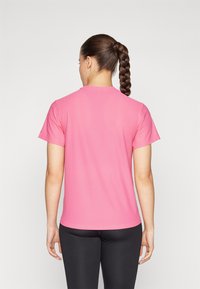 T-shirt a maniche corte con scollatura rotonda di un vivace colore rosa, realizzato in un tessuto leggero e morbido. La vista posteriore mostra un design pulito senza adornamenti.