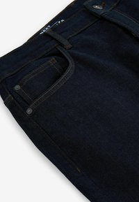 Dunkelblaue Jeans aus Denim mit kontrastierenden orangen Nähten, einem Knopfverschluss und einem kleinen Taschendetail. Glatte, strapazierfähige Stoffstruktur.