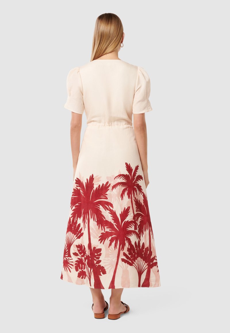 Crème-kleurige jurk met korte pofmouwen. Heeft een rode palmboomprint op de rok, vloeiende stof en een natuurlijke taille.