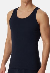 Mørkeblå tanktop lavet af bomuld, med et klassisk ærmeløst design, rund halsudskæring og en glat, tætsiddende tekstur.