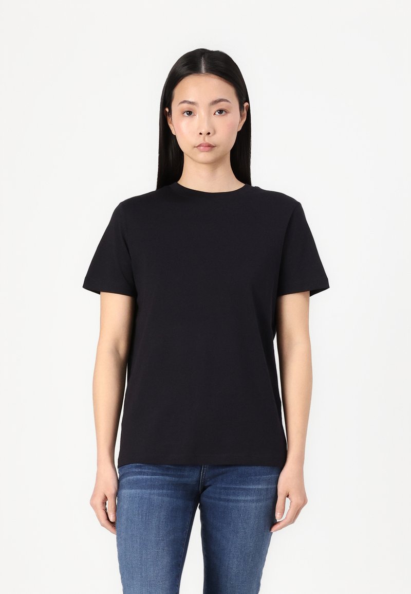 Black short-sleeve t-shirt made of cotton, featuring a classic crew neck and a relaxed fit. Worn with blue jeans.
