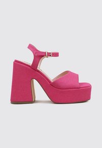 Sandalias de plataforma rosas con una parte superior de tejido texturizado, diseño abierto en la puntera, tira de tobillo y un tacón grueso. La suela presenta un ligero acento marrón.