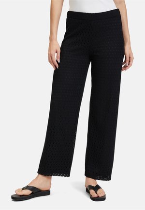 Pantaloni neri a gamba larga realizzati in tessuto strutturato con un motivo a taglio a diamante. Un elastico in vita e una vestibilità rilassata offrono comfort.