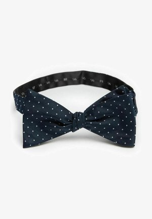 Mörkblå fluga med vita prickar, tillverkad av texturerat tyg, med en knuten mittdel och justerbar svart rem.