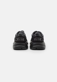 Sneaker nere con tomaia in rete, dettagli testurizzati e marchio "HUGO" sul tallone. Punta arrotondata e suola imbottita.