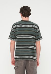 Κοντομάνικο, ριγέ t-shirt σε σκούρο πράσινο χρώμα, με οριζόντιες λευκές και κίτρινες ρίγες. Κατασκευασμένο από υφασμάτινη υφή με άνετη γραμμή.