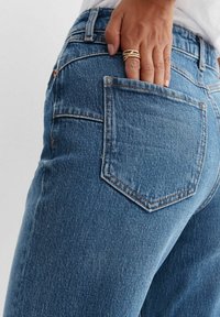 Ljust blå denimjeans med hög midja, raka ben och en bakficka med synlig sömdetalj.