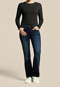 Chemise noire à manches longues associée à un jean évasé bleu foncé avec poches avant et fermeture par boutons. Le look est complété par des baskets blanches.