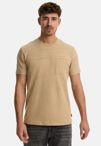 Kortærmet beige t-shirt med et struktureret overpanel, rund hals og en lille brystlomme, lavet af blødt, let materiale.