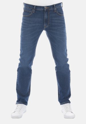 Jeans ajustados de mezclilla azul oscuro con diseño de cinco bolsillos, detalles de costura sutiles y una textura ligeramente desteñida. Combinados con zapatillas blancas.