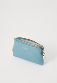 Blue textured leather zippered pouch with gold zipper and keyring, "COCCINELLE" logo in gold lettering on front.