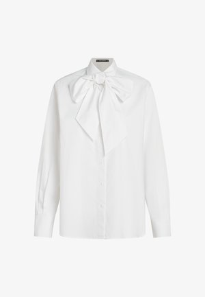 Balta mygtukinė marškinėliai su ilgomis rankovėmis, su dideliu palanku ant apykaklės, pagaminti iš lygaus audinio su švariu tekstūra.