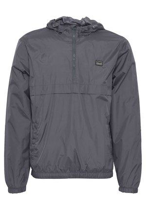 Grauer Windbreaker mit einem Halb-Zip-Ausschnitt, elastischen Bündchen und Saum. Verfügt über ein kleines Logo auf der linken Brust. Leicht und mit glatter Textur.