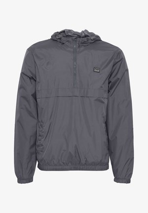 Grauer Windbreaker mit einem Halb-Zip-Ausschnitt, elastischen Bündchen und Saum. Verfügt über ein kleines Logo auf der linken Brust. Leicht und mit glatter Textur.