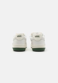 Hvide Vans sneakers med en grøn sål og grønt logo på hælen. Har glat læder og polstret krave for komfort.
