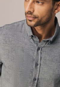 Overhemd met knoopsluiting in een gestructureerde grijze stof, voorzien van een traditionele kraag, donkere knopen aan de voorkant en een smal slim fit design.