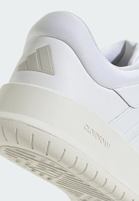 Chaussure de sport blanche avec une tige en cuir lisse, un col rembourré, des détails Cloudfoam sur la semelle et une semelle en caoutchouc texturé.