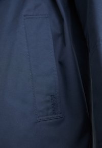 Marine jasstof met een gladde textuur, voorzien van een gestikte zak aan de zijkant en het reliëf 'Barbour' merk.