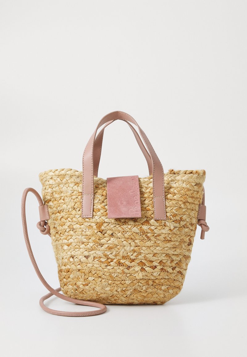 Saco de palha trançada com alças em couro rosa claro e um patch de couro combinando na parte da frente. Apresenta uma forma curvada e alça de ombro destacável.