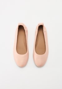 Lys rosa ballettsko med en glatt læroverflate, rund tå og myk, elastisk kant rundt åpningen. Lett og enkel design.
