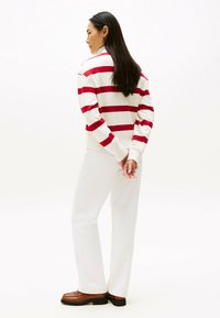 Rød og hvid stribet sweatshirt, afslappet pasform, parret med hvide bukser og brune loafers. Glat stof med lange ærmer og synlige sømme.