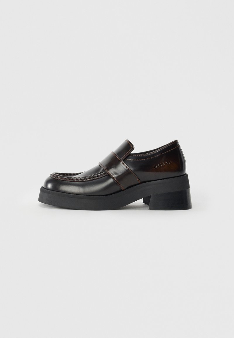 Brown leather loafers with a chunky black heel, featuring a stitched design and a strap across the upper for added detail.
