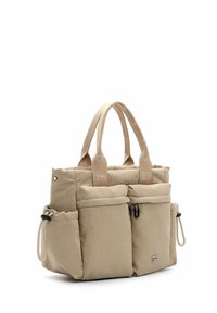 Beige tote bag lavet af blødt stof, med to frontlommer, lynlåslukninger og forstærkede håndtag med diskret branding.