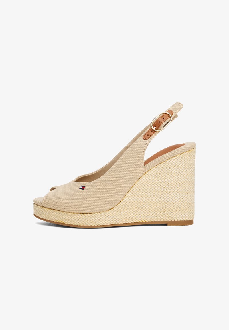 Beige wedge sandals with a peep toe design, canvas upper, woven jute-like midsole, and a tan adjustable strap featuring a gold buckle.