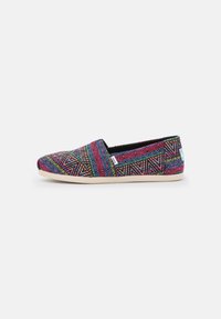 Scarpe slip-on colorate con un audace motivo geometrico in rosa, blu, verde e nero, caratterizzate da una tomaia in tessuto testurizzato e una suola leggera.