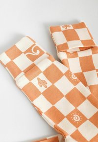 Chaussettes à carreaux orange et crème avec des motifs fantaisistes, y compris des tourbillons et une banane, en tissu doux en mélange de coton.
