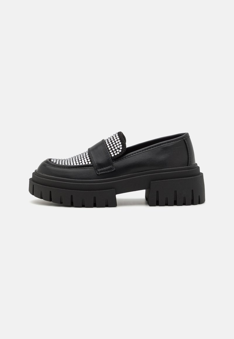 Crne loafers c sa zakovikama na gornjem delu, sa debelim platformama i rebrastom teksturom. Glatki kožni materijal i dizajn koji se lako obuva.
