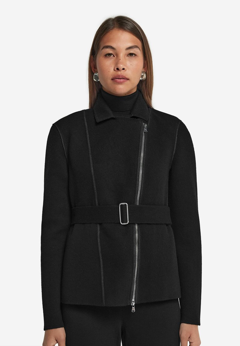 Svart ullblandad jacka med en strukturerad passform, som har en dragkedja framtill, hög krage och ett bälte i midjan. Accenterad med kontrasterande sömmar.