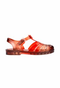 Sandalias rojas translúcidas con un diseño abierto, tiras cruzadas, hebilla ajustable y una suela de goma sólida con un acabado texturizado.