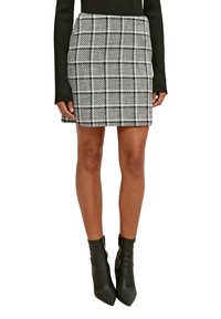 Black and white checkered mini skirt made from textured fabric, featuring a fitted design and paired with black ankle boots.