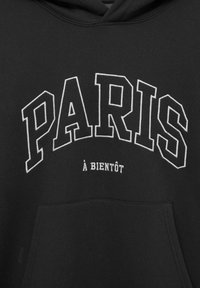 Sudadera negra con capucha que presenta un texto impreso en blanco que dice "PARIS" en el pecho, con "à bientôt" debajo. Diseño de bolsillo delantero incluido.