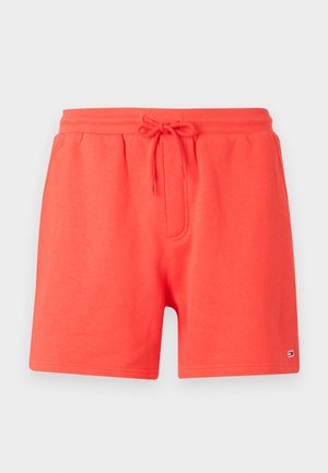 Röda bomullsshorts med dragsko i midjan, framficka och diskret logga längst ner till vänster. Slät textur och avslappnad design.