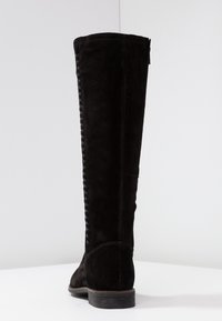 Bota alta de ante negro con acabado texturizado, detalle trenzado en el lateral y tacón bajo apilado. Silueta suave y aerodinámica.