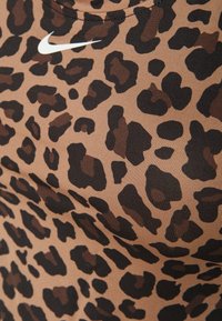 LEOPARDPRINT AURLEN-SPORT TANKTOP IN BRUIN EN ZWART, MET EEN GERIBBELDE TEXTUUR EN EEN WITTE NIKE-LOGO OP HET MATERIAAL.