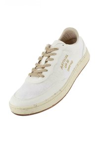 Zapatilla de lona blanca con cordones beige, punta redonda, parte superior texturizada y un sutil logo en el costado. Presenta una suela de goma de color claro.