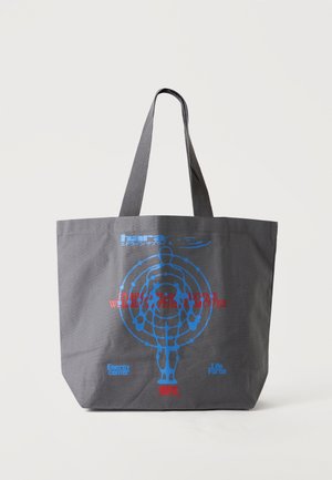 Sac fourre-tout gris foncé avec une silhouette humaine bleue entourée de cercles concentriques et un texte rouge et bleu à l'avant.