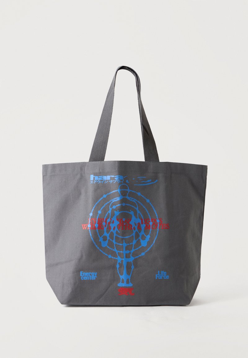 Sac fourre-tout gris foncé avec une silhouette humaine bleue entourée de cercles concentriques et un texte rouge et bleu à l'avant.