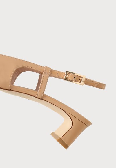 Chaussure slingback en cuir beige avec boucle carrée dorée et petit talon courbé sur fond blanc.