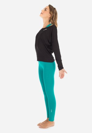 Black long-sleeve top paired with teal leggings. The top has a loose fit and is made of soft fabric; leggings are form-fitting and smooth.