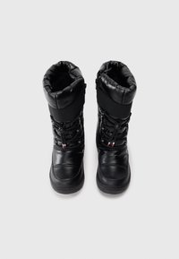 Botas de invierno negras con parte superior acolchada, cierre con cordón y suela de goma texturizada. Presentan un zipper lateral y acentos de color en contraste.